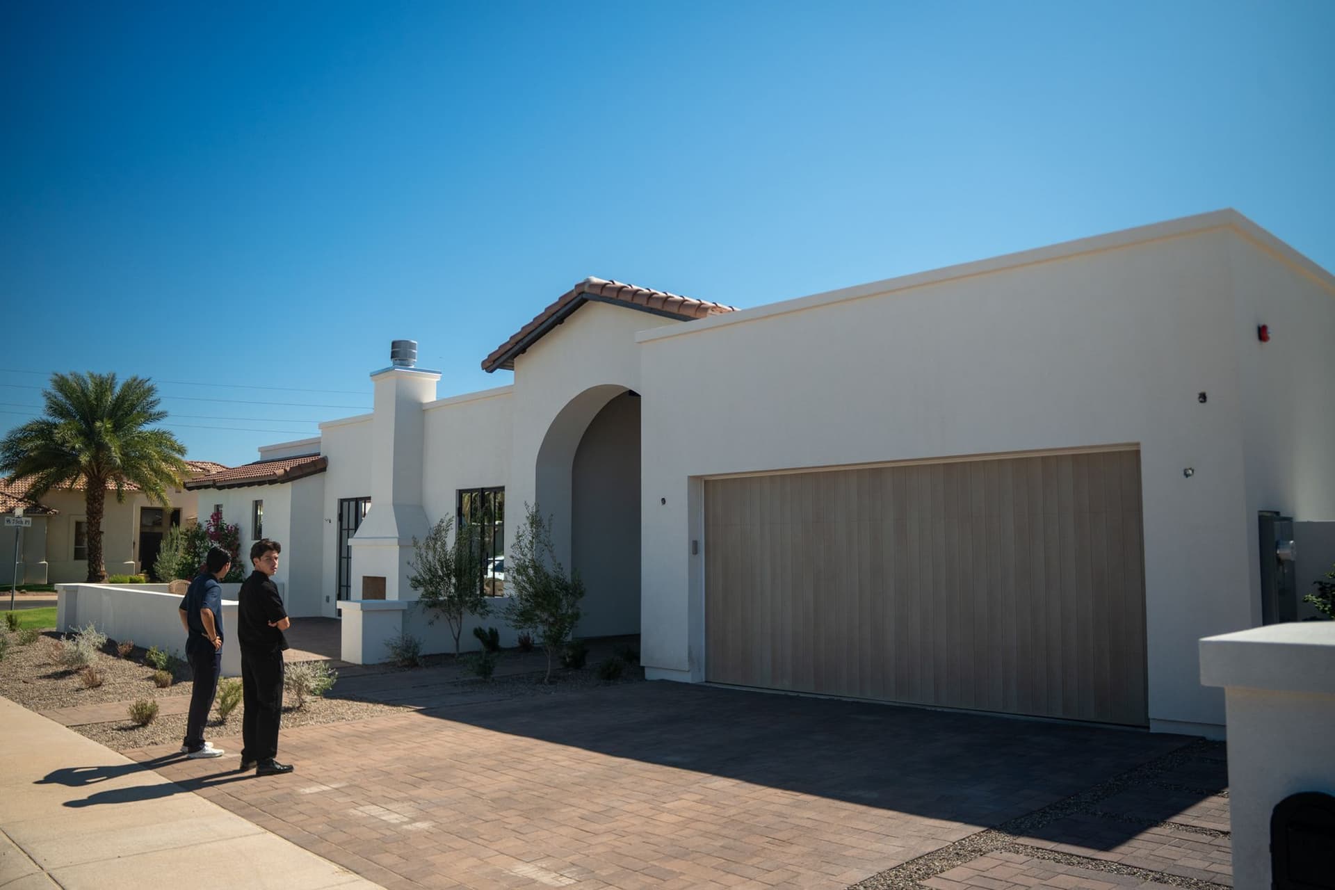 Two people outside a completed white stucco residence