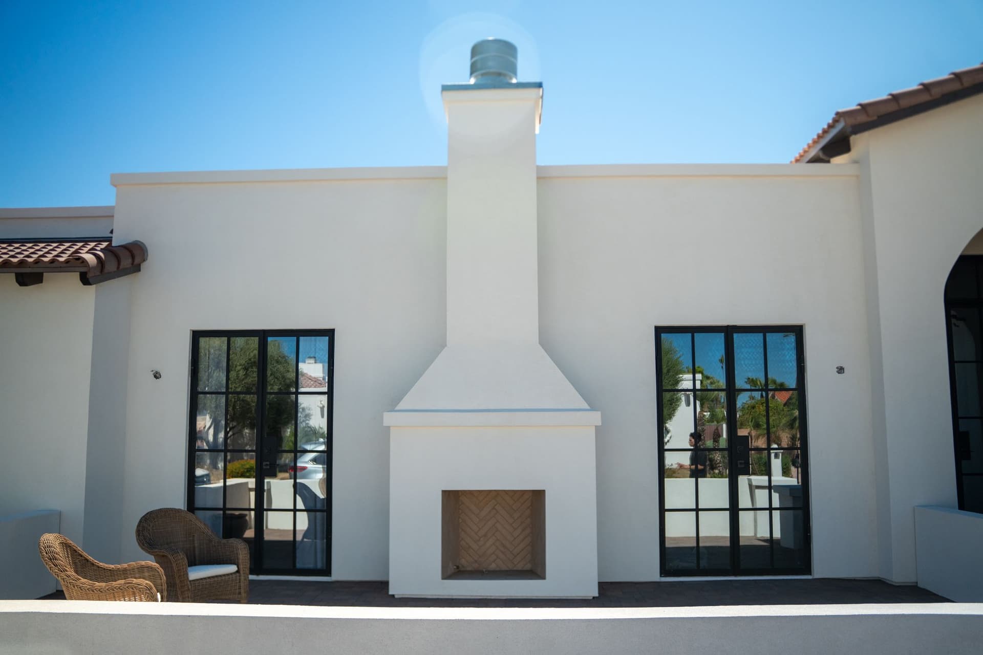 Finished courtyard with a white stucco fireplace and black-framed glass doors