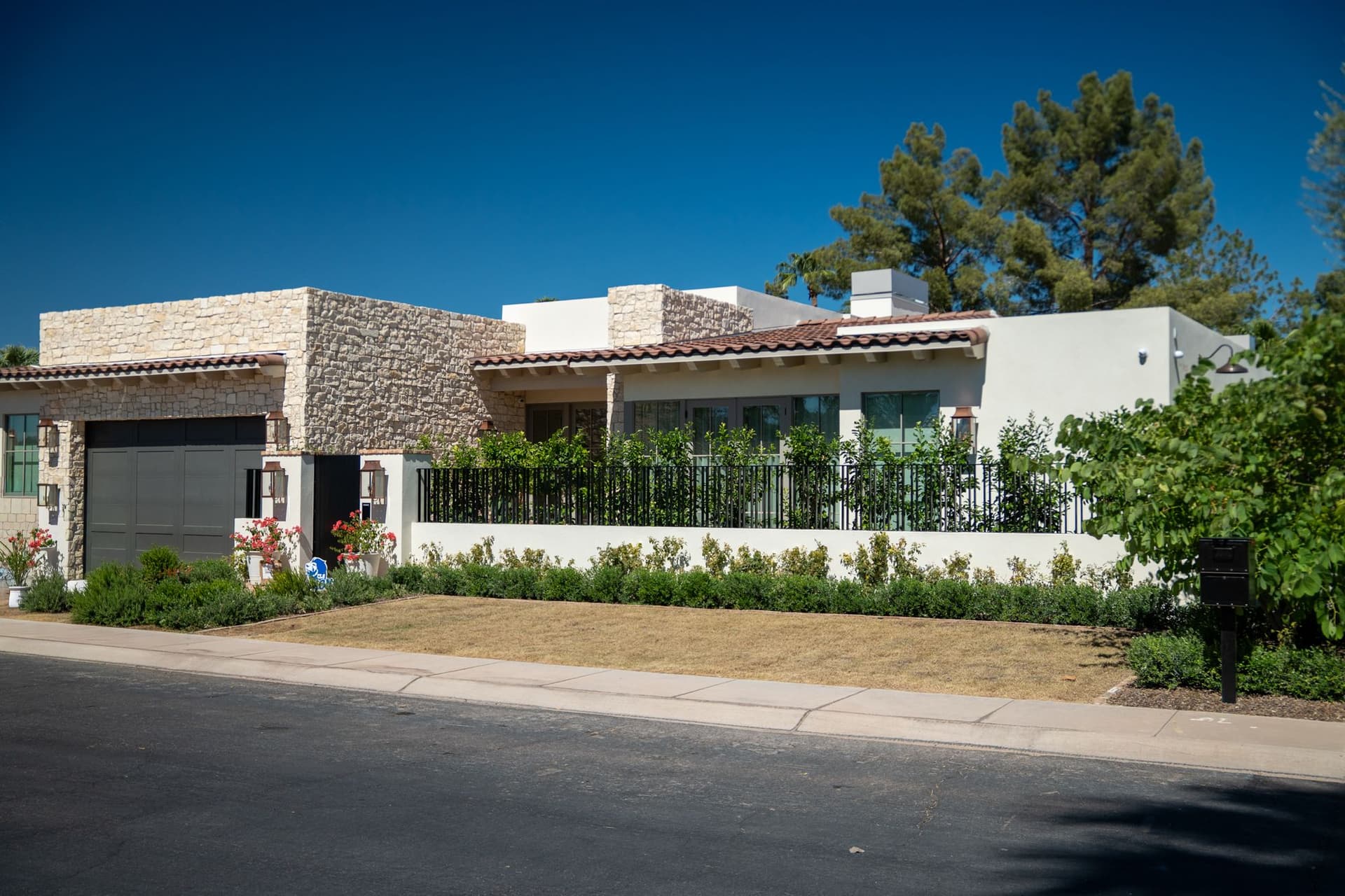 Completed residence with white stucco walls, stone cladding and dark metal railings