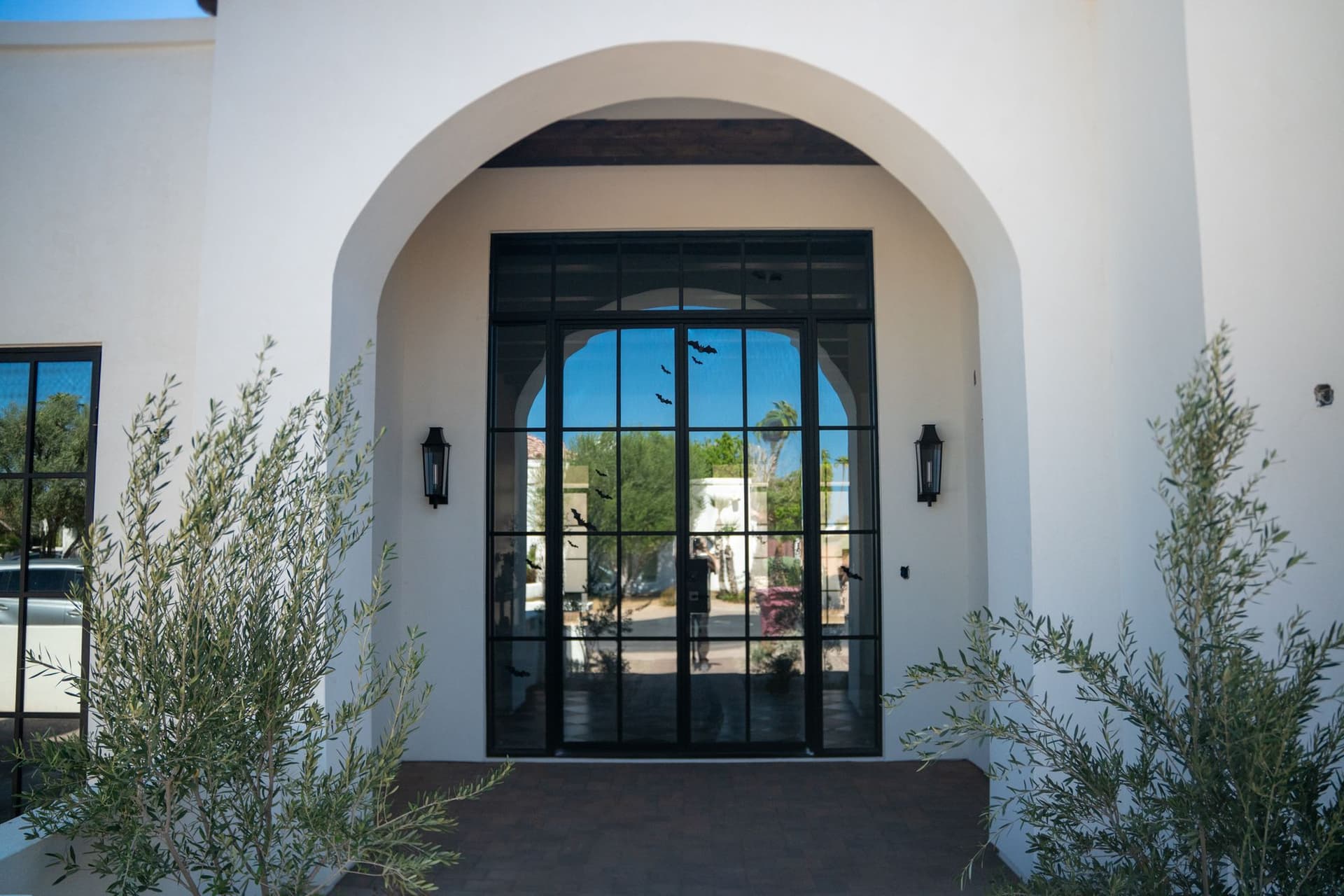 Centered arched stucco entrance with a black metal and glass front door