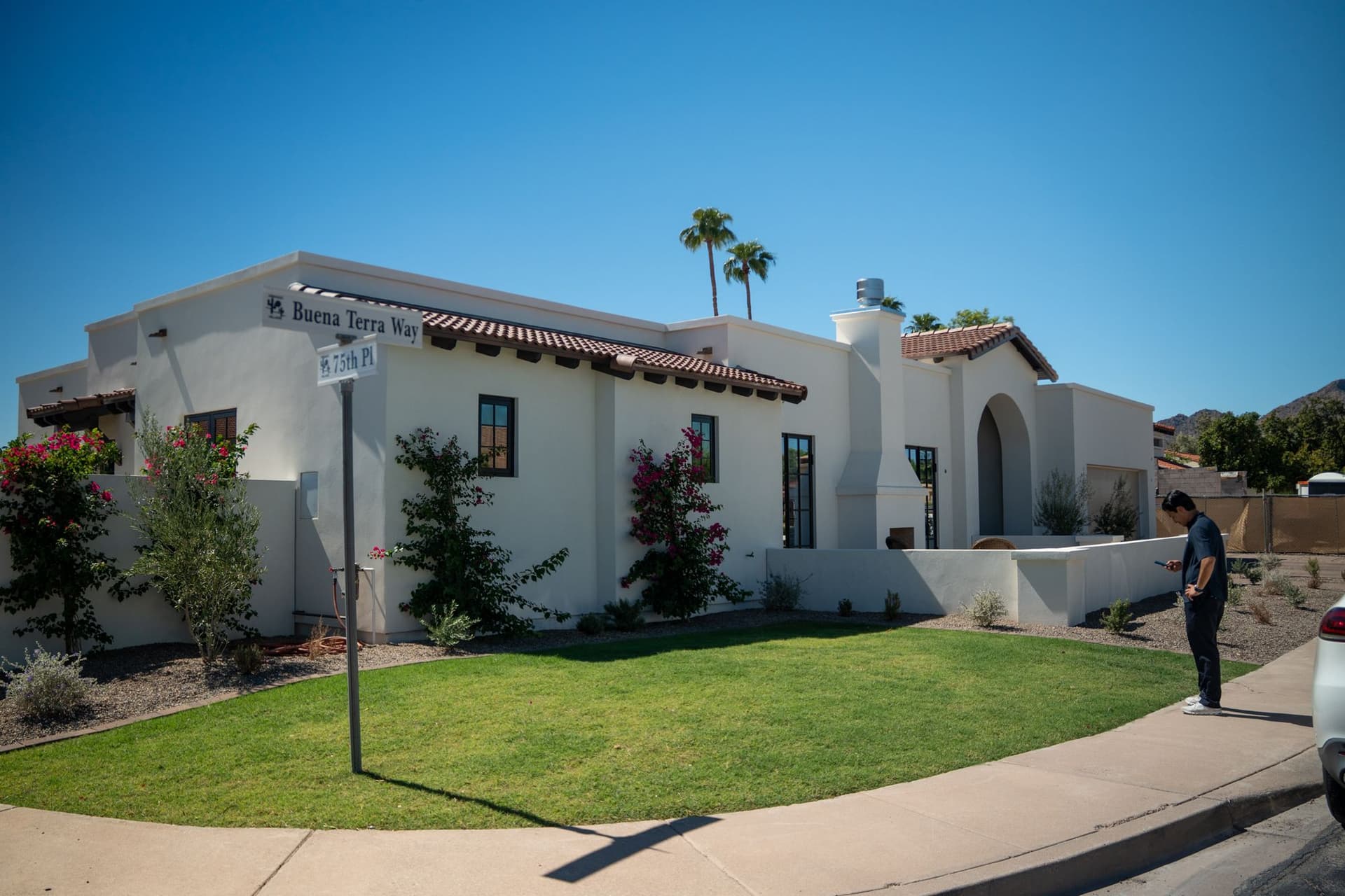 Finished white stucco home with tiled eaves and an arched entry