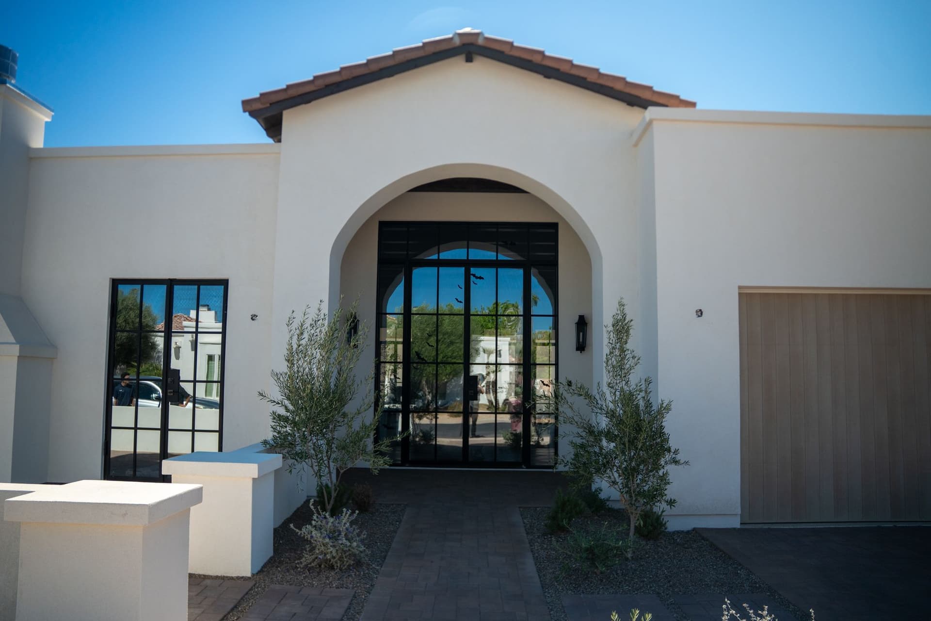 Completed home exterior with an arched white stucco entryway and wood garage door