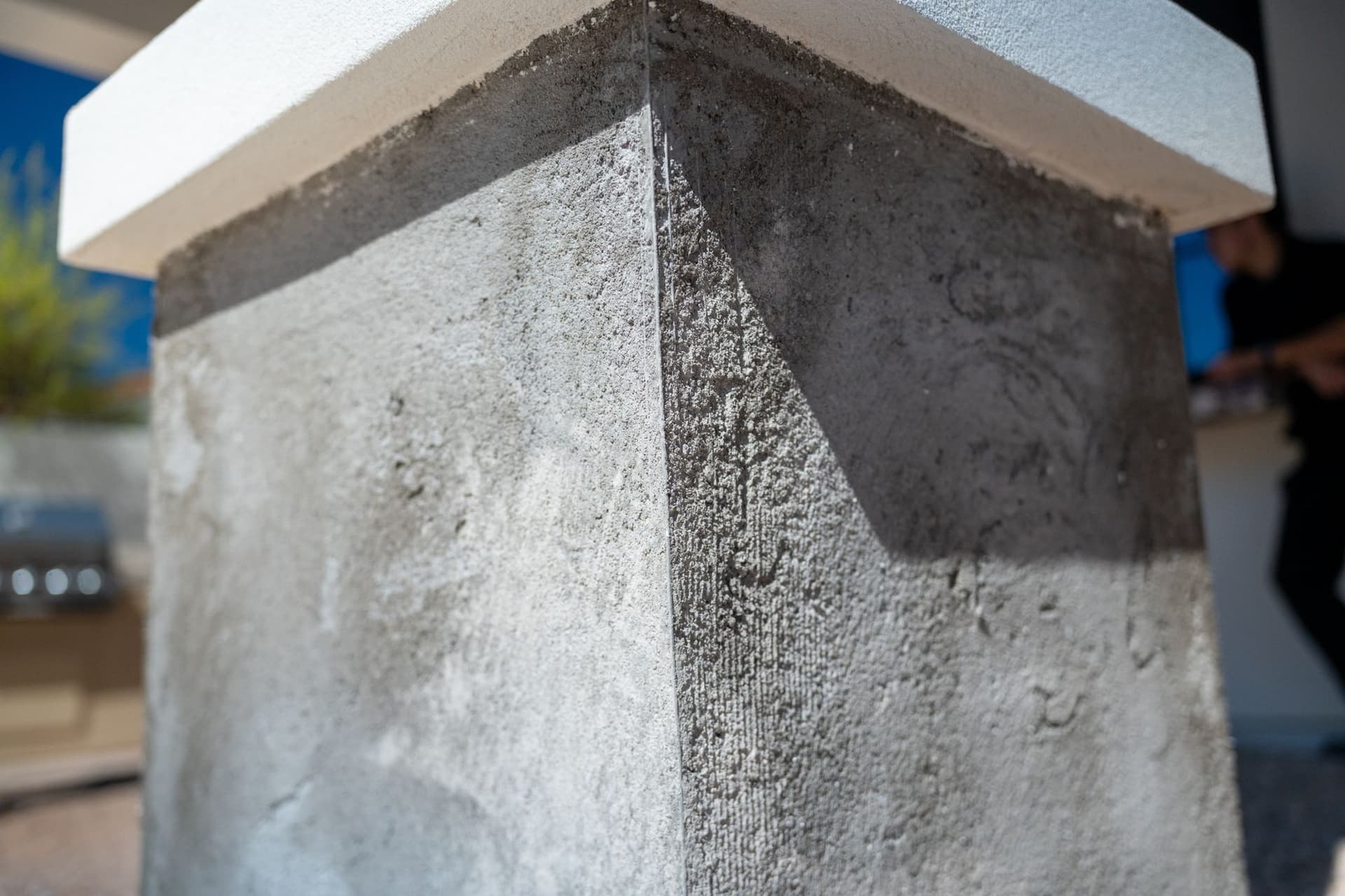 Close view of a grey stucco base coat around a column corner