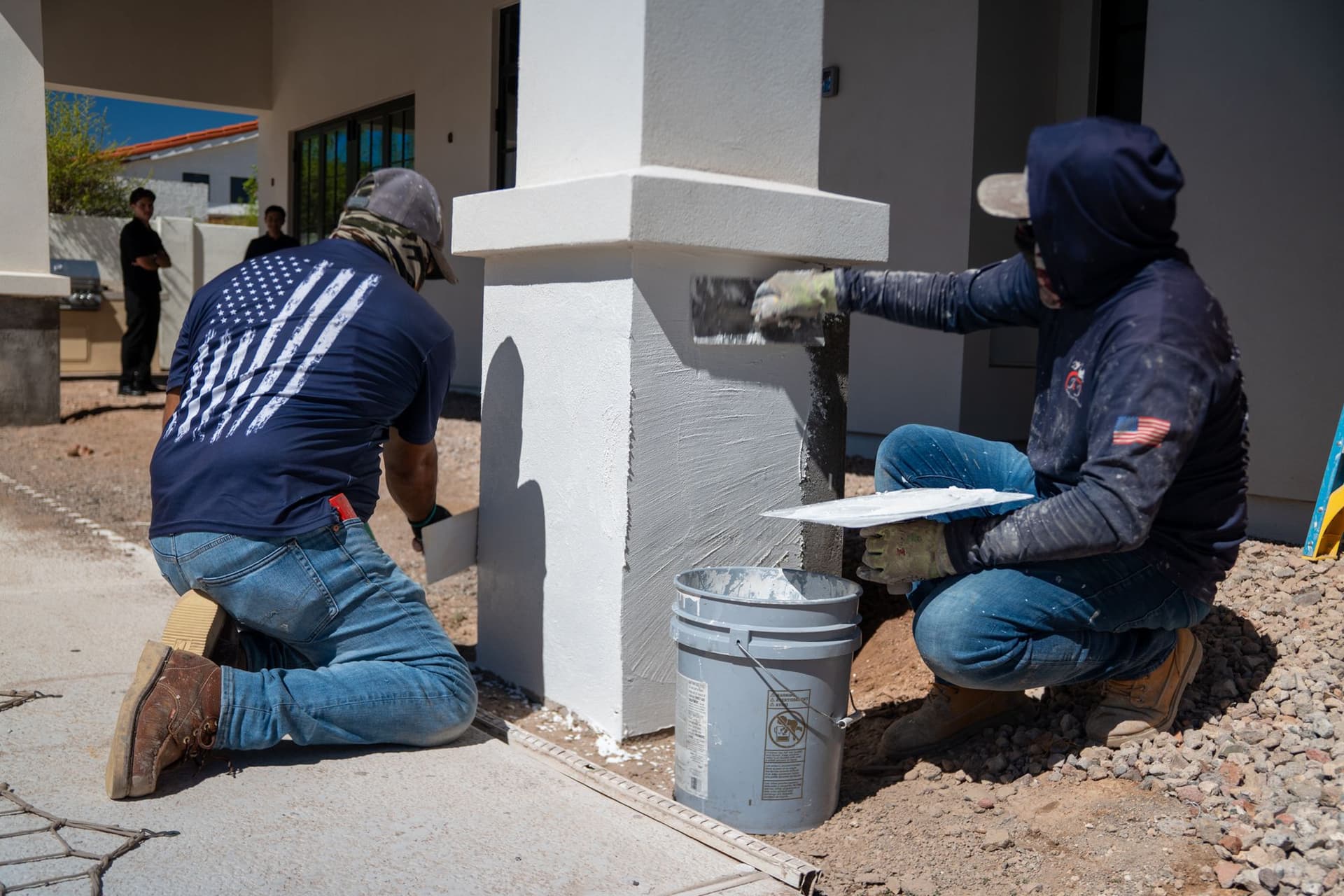Two J&J Pros crew members applying white stucco to an exterior column