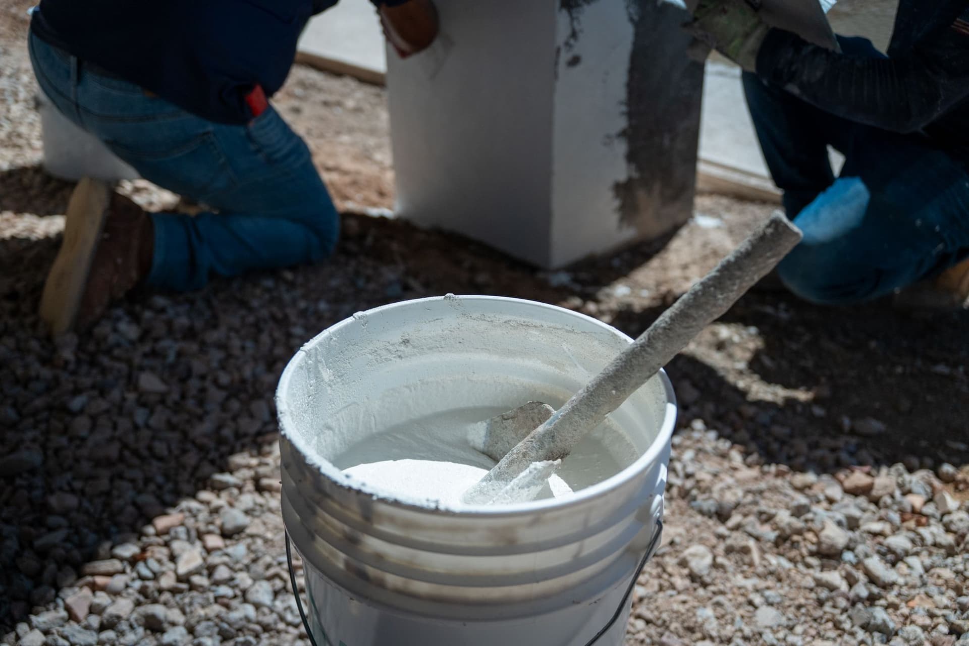 Bucket of white stucco material and a hand tool beside the crew's work area