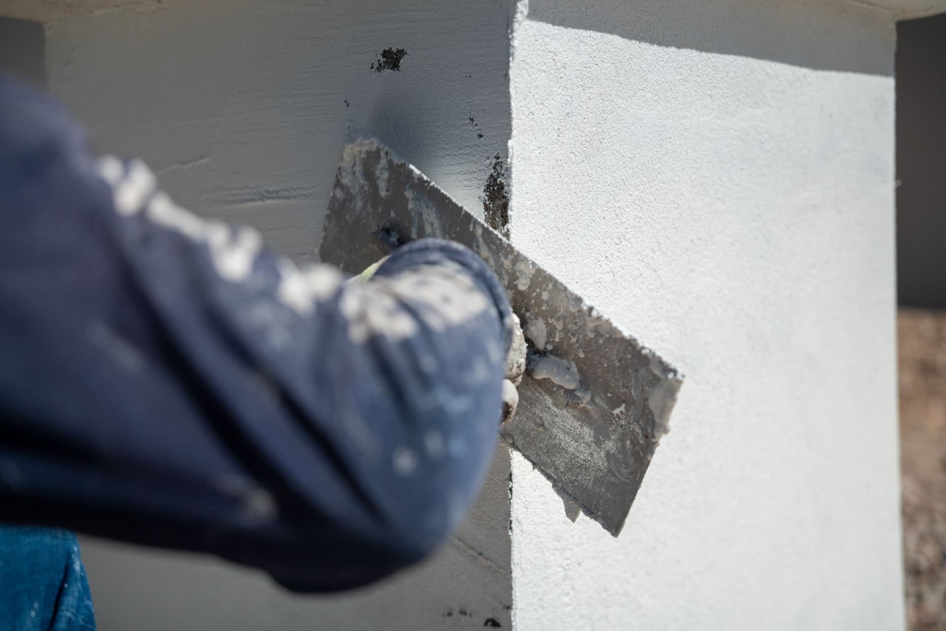 J&J Pros crew member troweling white stucco over a grey base coat